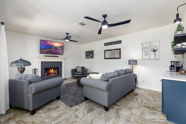 living room with a brick fireplace, visible vents, and ceiling fan