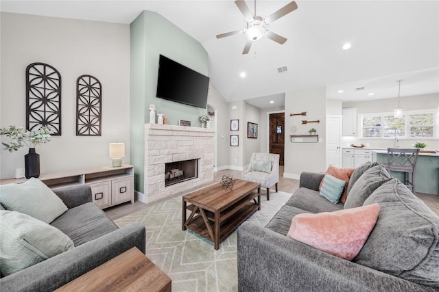 living room with lofted ceiling, recessed lighting, a fireplace, baseboards, and light wood-style floors