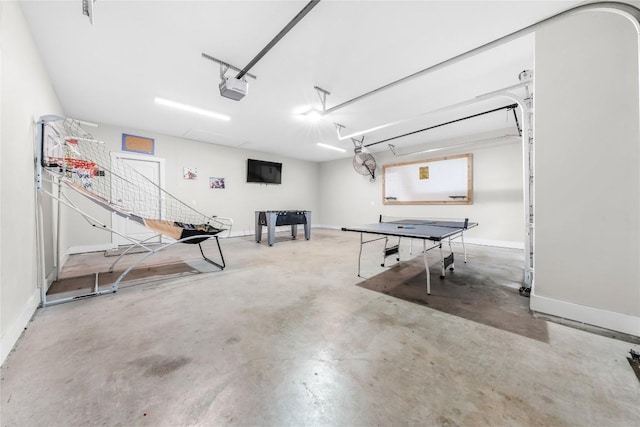 game room with a garage, baseboards, and unfinished concrete floors