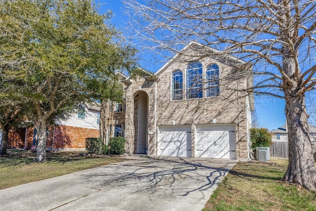 traditional-style home with brick siding, driveway, an attached garage, and fence