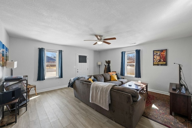 living area featuring light wood finished floors, a ceiling fan, and baseboards