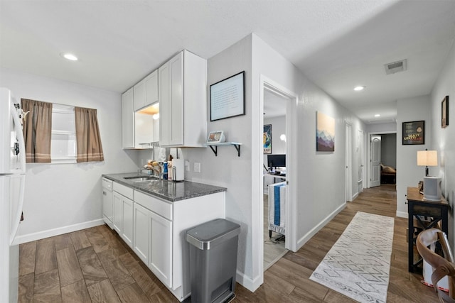 kitchen featuring dark wood-style flooring, a sink, and white cabinetry