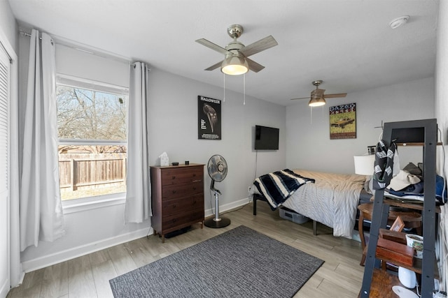 bedroom with light wood-style floors, multiple windows, baseboards, and a ceiling fan