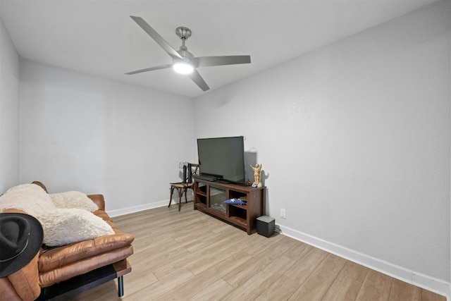 living area featuring baseboards, ceiling fan, and light wood finished floors