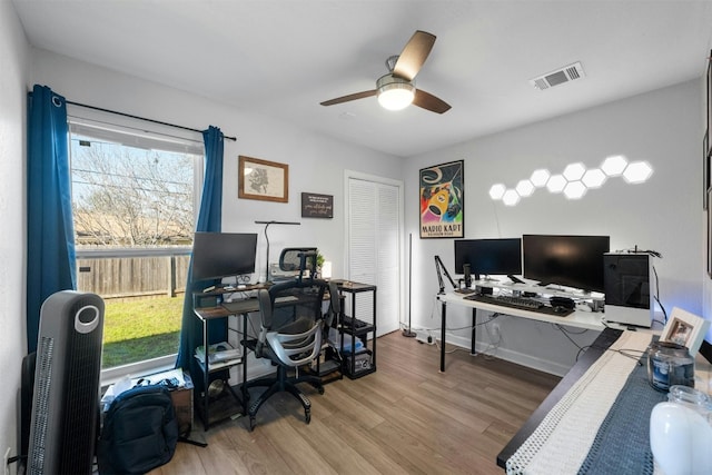 home office featuring a ceiling fan, visible vents, baseboards, and wood finished floors