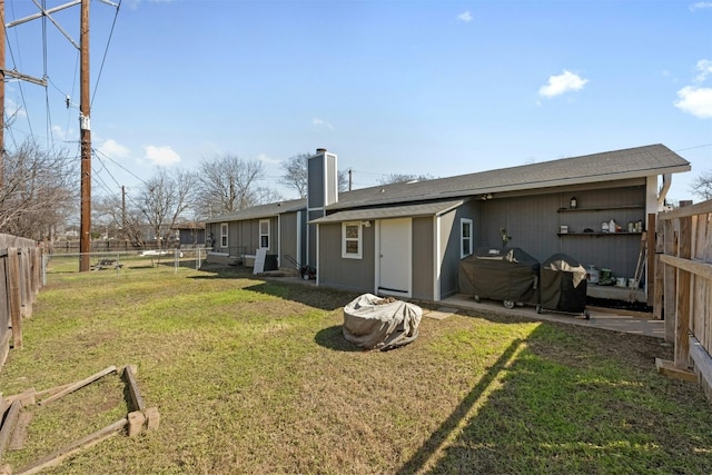 rear view of house featuring a fenced backyard, a chimney, and a yard