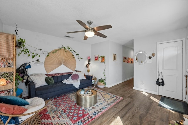 living room featuring ceiling fan, wood finished floors, visible vents, and baseboards