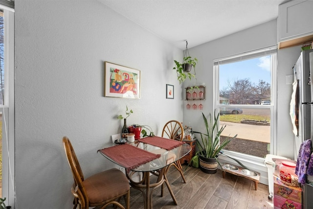 dining area with a textured wall and wood finished floors