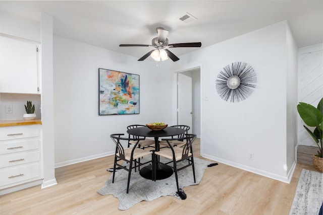 dining area with baseboards, visible vents, ceiling fan, and light wood finished floors