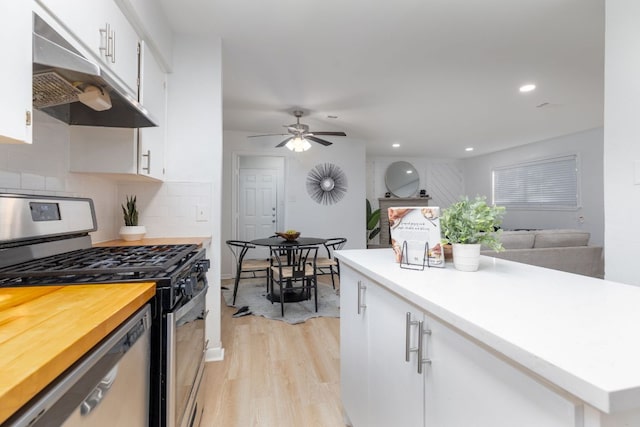 kitchen featuring light wood-style flooring, under cabinet range hood, stainless steel appliances, white cabinets, and decorative backsplash