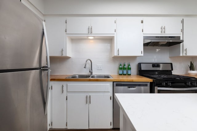 kitchen with tasteful backsplash, appliances with stainless steel finishes, light countertops, under cabinet range hood, and a sink