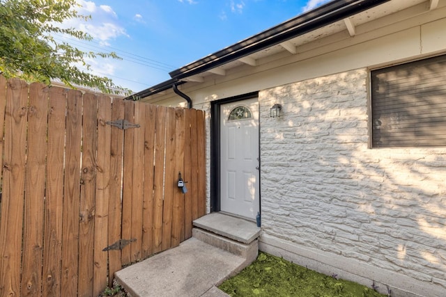 property entrance featuring stone siding, a gate, and fence