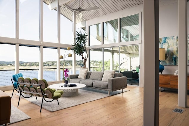 719 Cutlass St, Austin, TX 78734 - living room with a high ceiling, a ceiling fan, light wood-type flooring, a water view, and a wall of windows