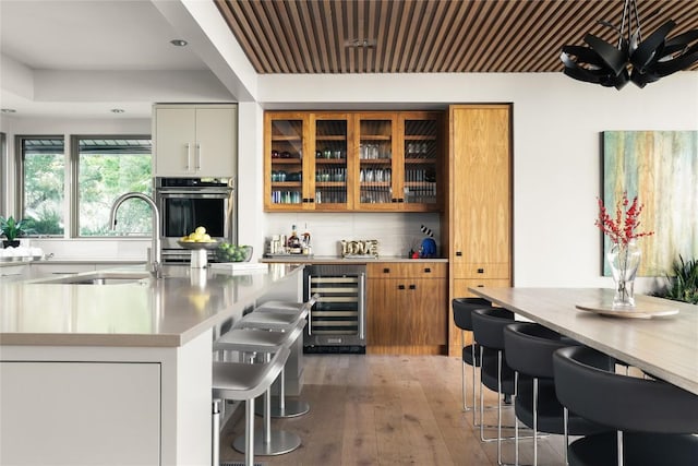 719 Cutlass St, Austin, TX 78734 - indoor dry bar featuring beverage cooler, stainless steel oven, light wood finished floors, and tasteful backsplash
