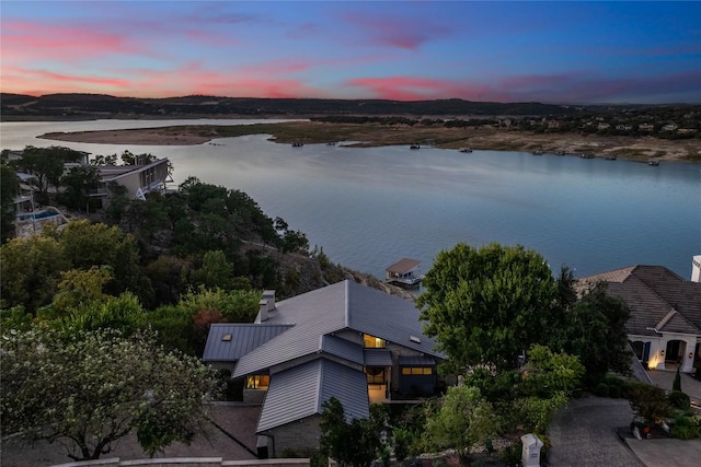 aerial view at dusk featuring a water view