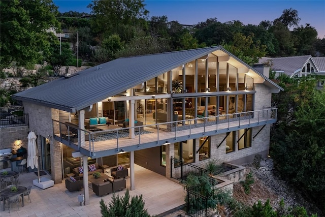 back of house at dusk with metal roof, a patio, and outdoor lounge area