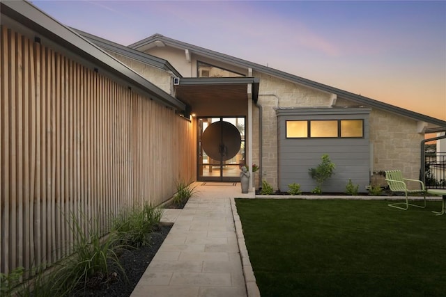 719 Cutlass St, Austin, TX 78734 - exterior entry at dusk featuring stone siding and a yard