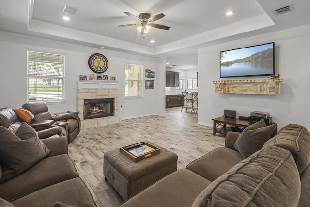 living room featuring a raised ceiling, visible vents, and light wood-style flooring