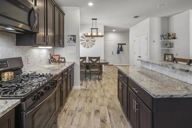 kitchen with stainless steel appliances, light wood-style floors, dark brown cabinets, light stone countertops, and tasteful backsplash