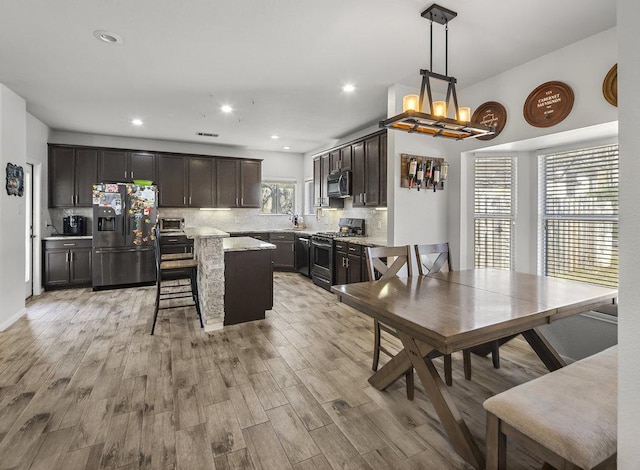 kitchen featuring appliances with stainless steel finishes, light wood-type flooring, a center island, and tasteful backsplash