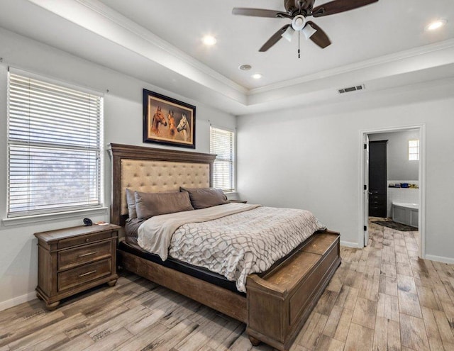 bedroom featuring visible vents, baseboards, light wood-style floors, a tray ceiling, and crown molding