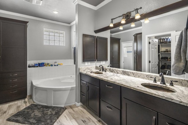 full bathroom with crown molding, a garden tub, and a sink