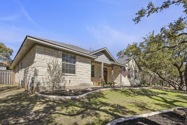 single story home featuring stone siding, fence, and a front yard