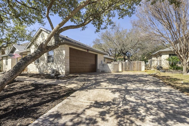 view of side of home featuring concrete block siding, concrete driveway, a gate, fence, and a garage