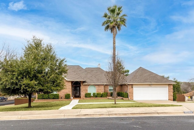 view of front facade with driveway, an attached garage, a front lawn, and a shingled roof