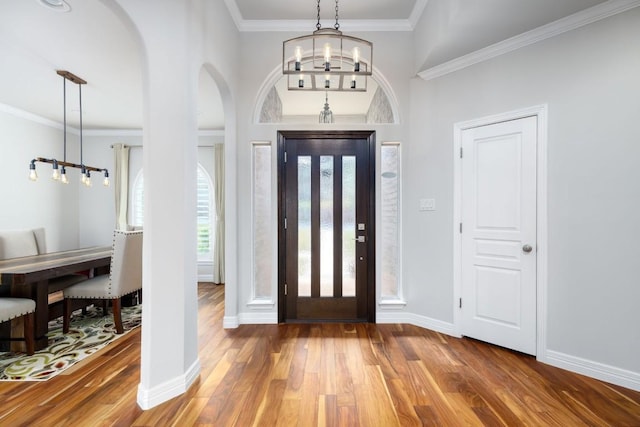 foyer with baseboards, crown molding, a chandelier, and wood finished floors