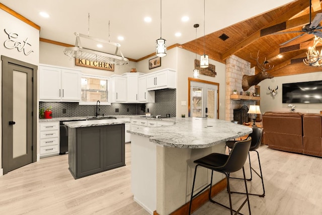 kitchen featuring light wood finished floors, decorative backsplash, open floor plan, a center island, and a sink