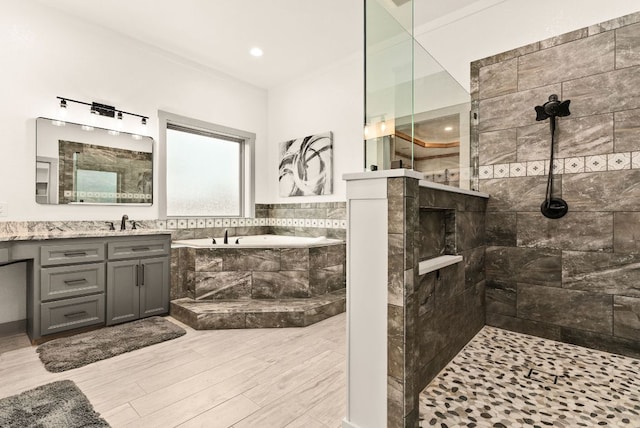 bathroom featuring a walk in shower, wood finished floors, a garden tub, and vanity