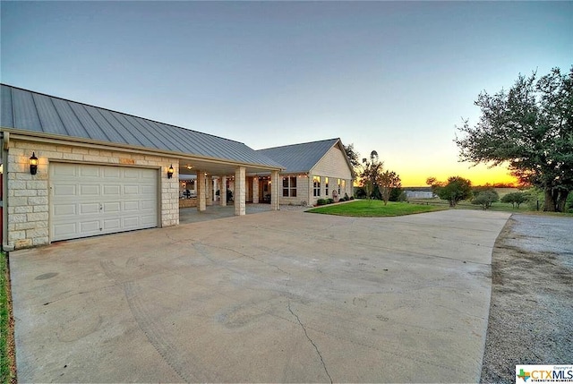 view of front of home with metal roof, driveway, a standing seam roof, and an attached garage