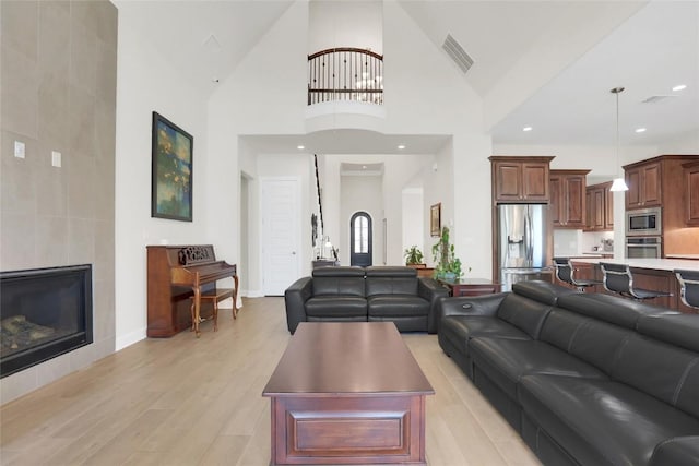 4104 Belisario Ct, Leander, TX 78641 - living room with light wood-style floors, high vaulted ceiling, and a tile fireplace