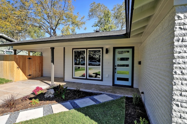 view of exterior entry with fence and a porch