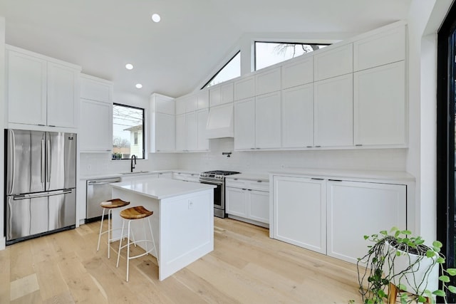 kitchen featuring white cabinets, stainless steel appliances, a sink, and a kitchen breakfast bar