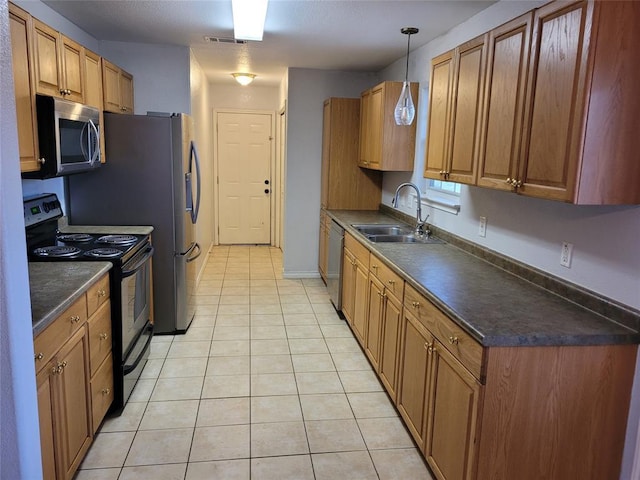 kitchen featuring light tile patterned floors, dark countertops, visible vents, appliances with stainless steel finishes, and a sink