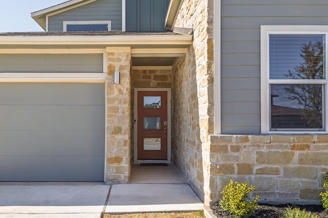 doorway to property with stone siding, board and batten siding, and an attached garage