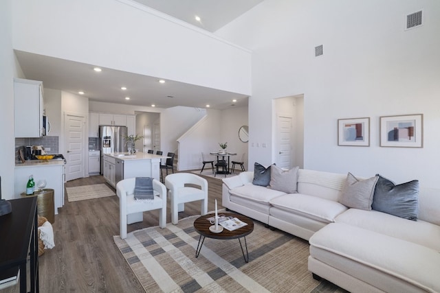 living area featuring a high ceiling, visible vents, dark wood-type flooring, and recessed lighting