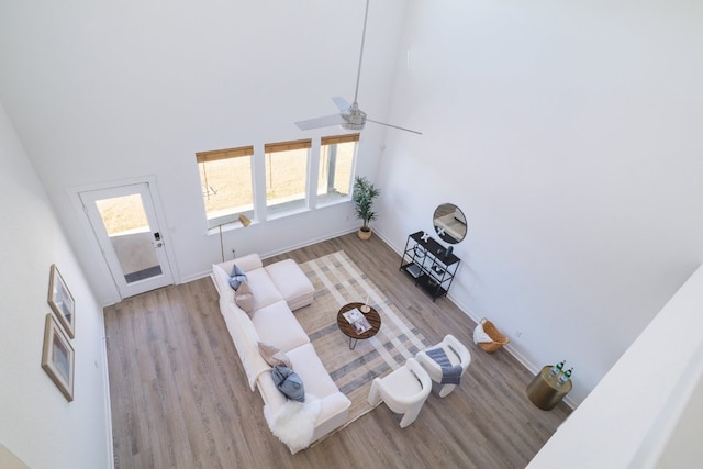 living area featuring a towering ceiling, baseboards, and wood finished floors