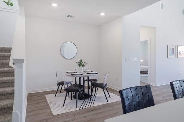 dining space with visible vents, baseboards, wood finished floors, stairs, and recessed lighting