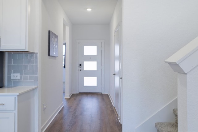 doorway with stairs, dark wood-type flooring, and baseboards