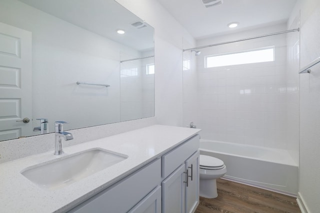 bathroom with visible vents, toilet, vanity, wood finished floors, and shower / bathtub combination