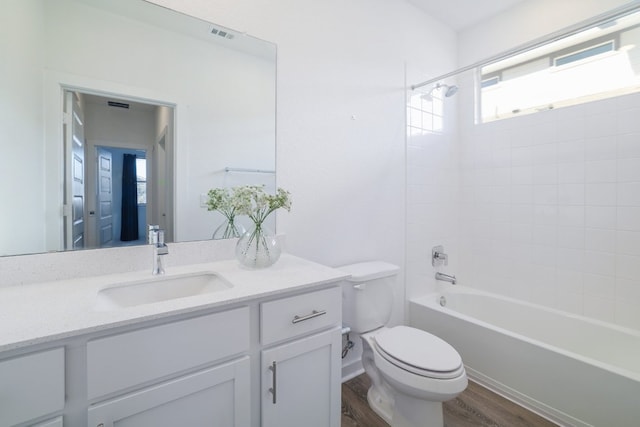 bathroom featuring visible vents, toilet, tub / shower combination, vanity, and wood finished floors