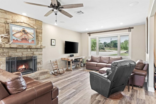 living room featuring baseboards, visible vents, ceiling fan, wood finished floors, and a fireplace