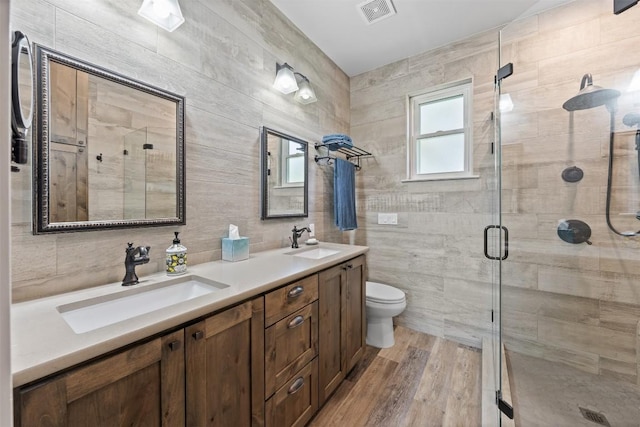 full bathroom with a stall shower, tile walls, visible vents, and a sink