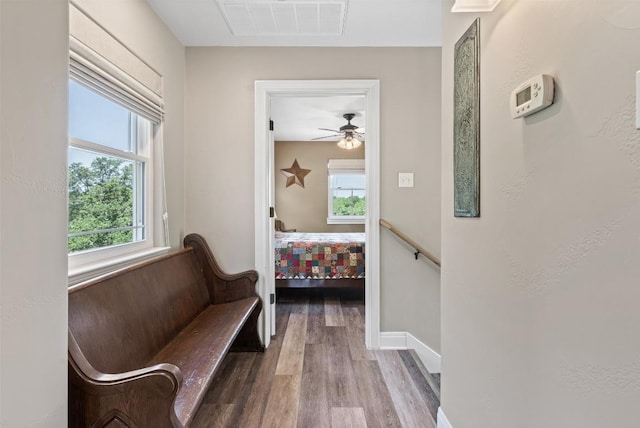 corridor with baseboards, wood finished floors, visible vents, and a healthy amount of sunlight