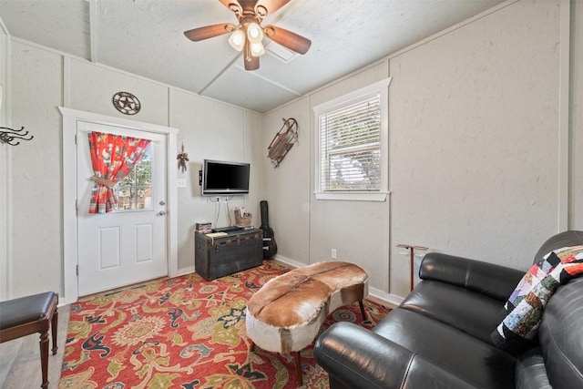 living area featuring ceiling fan and baseboards