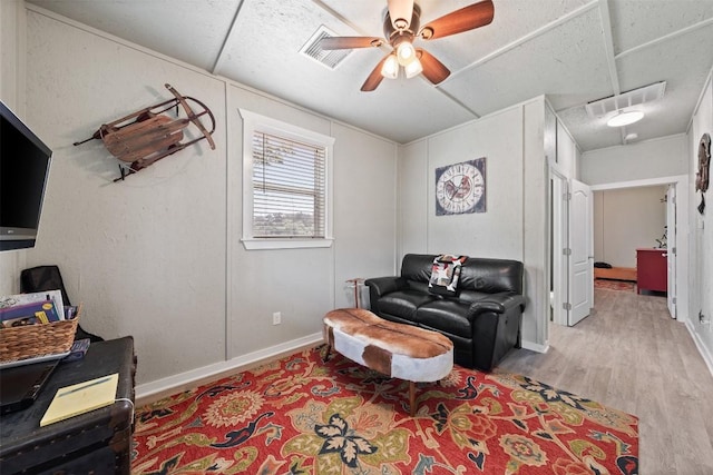 living area with visible vents, ceiling fan, baseboards, and wood finished floors