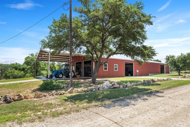 view of front of property featuring driveway, a detached garage, an outbuilding, an outdoor structure, and a carport